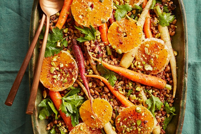 Lacto-fermented carrots with grain, orange and pistachio salad A green platter topped with grains, slices of orange, fermented carrots and crushed green pistachio nuts