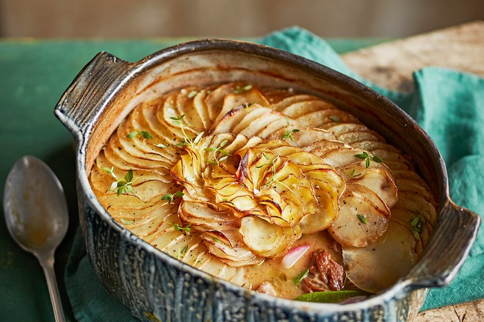 Lamb and turnip summer hot pot A speckled baking dish filled with a stew and layered with thin and crispy slices of turnip on top