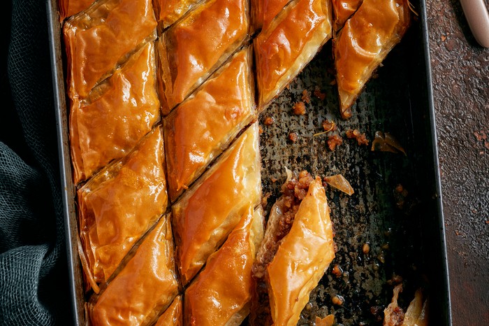 Sticky orange and ginger baklava A black baking tray filled with crispy filo pastry triangles