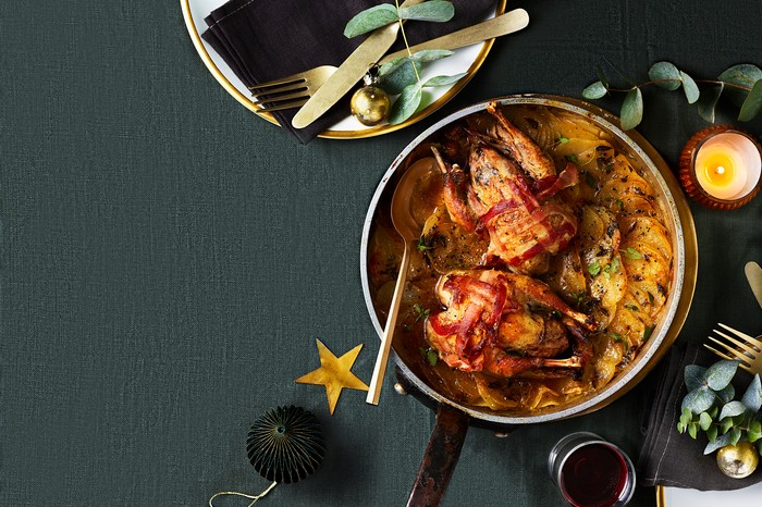 Roast partridge with one-pan boulangère A bowl filled with two roast partridges topped with crispy bacon with layered potatoes underneath