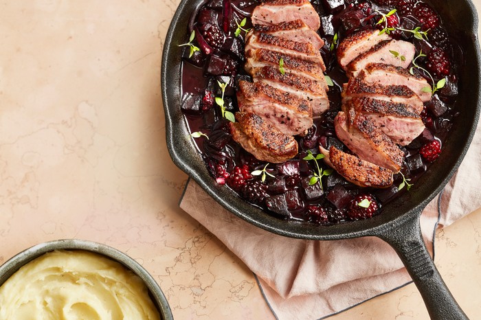 Duck breast with blackberry and beetroot A cast iron pan with two sliced duck breasts surrounded by blackberries and chopped beetroot