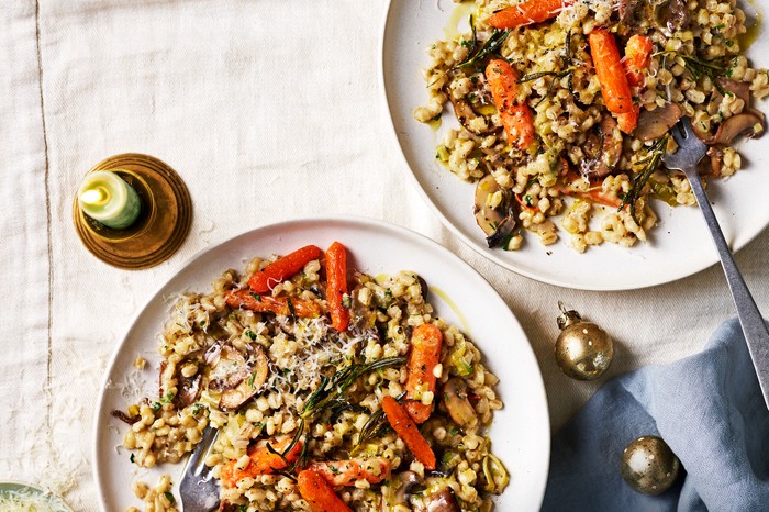 Mushroom pearl barley risotto with roasted carrots Two bowls filled with barley risotto and topped with orange roast carrots