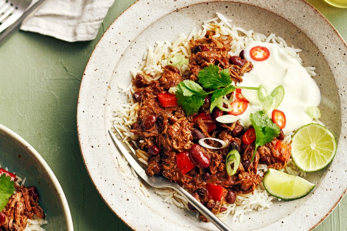 Slow cooker brisket chilli A plate of beef brisket with rice and lime wedges