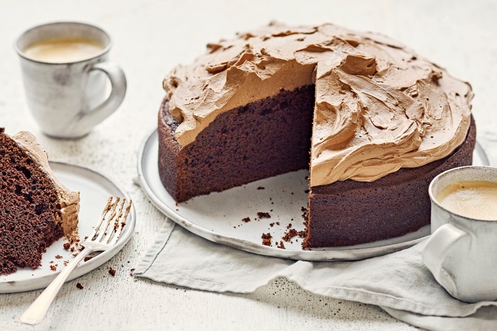 A frosted chocolate cake with tea on the side