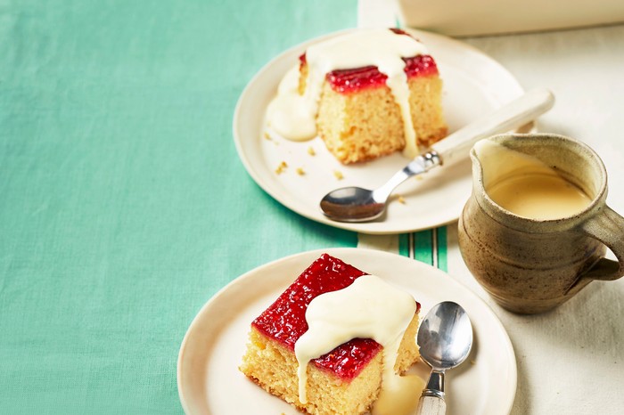 Jam and coconut sponge slices on two plates, topped with custard