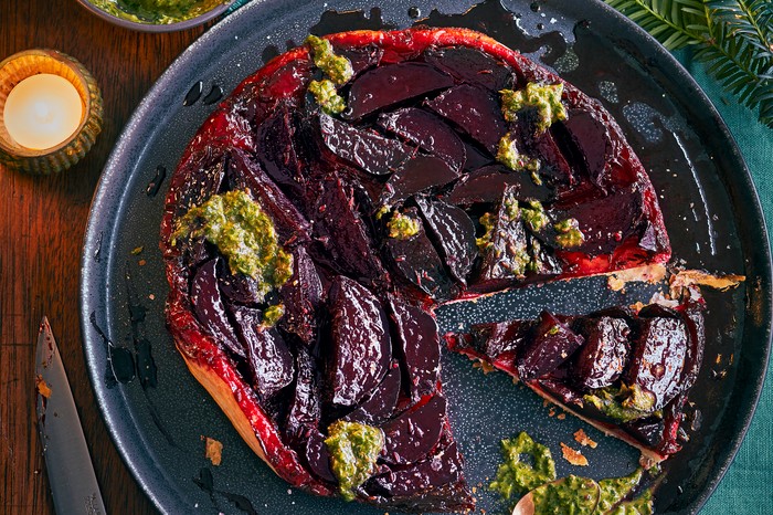 Beetroot tarte tatin A round puff pastry tart topped with purple beetroots and green pesto