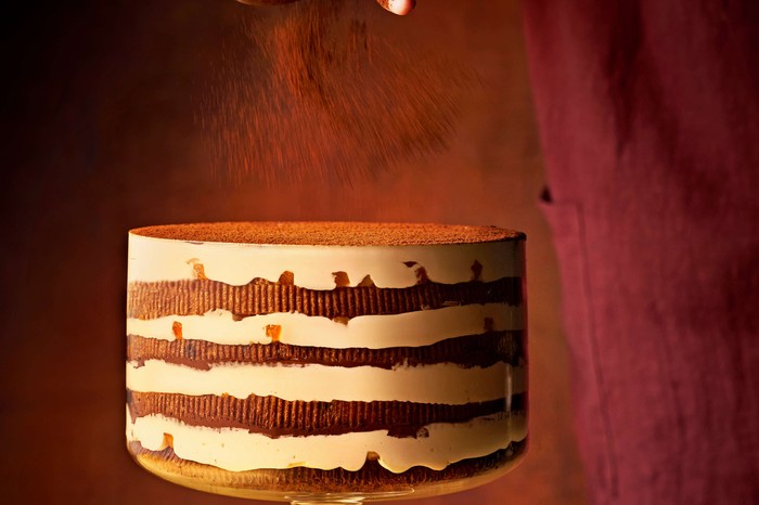 A large tiramisu panettone on a cake stand