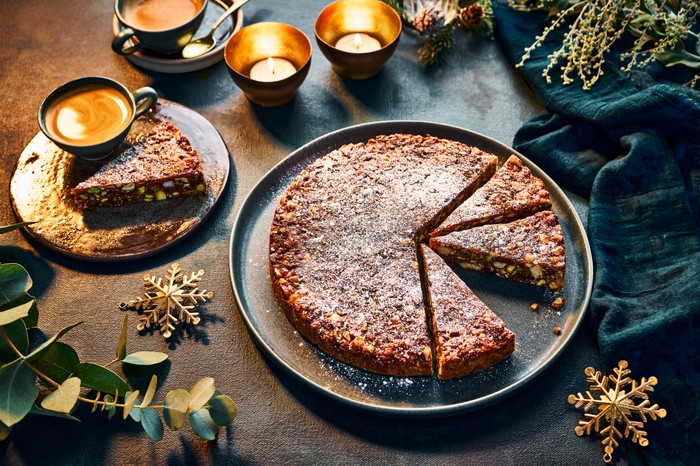 Panforte cut into slices on a plate, with tealights around