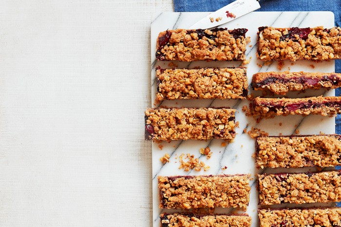 Pear and blackberry crumble bars A marble chopping board topped with slices of oaty bars