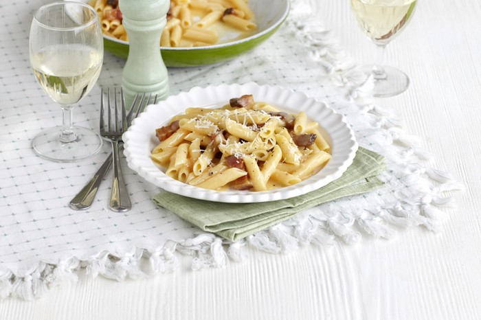 Penne Carbonara Recipe A plate of penne pasta with white wine on the side