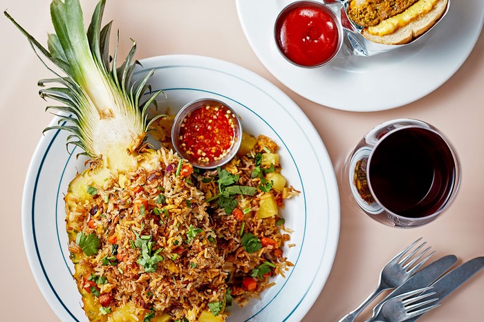 Pineapple-fried-rice Pineapple filled with fried rice on a plate next to a ramekin of chilli sauce