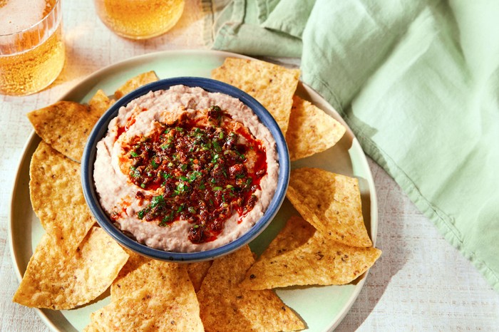Pinto bean dip Dip in a small blue bowl with tortilla chips and drinks on the side