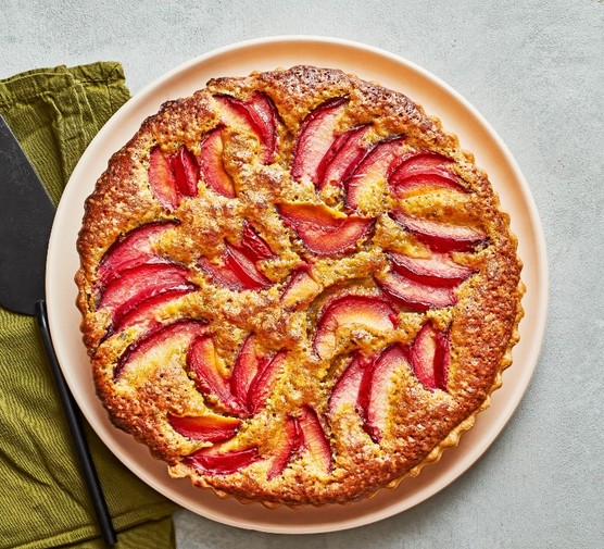 A plum tart on a peach plate with an olive green napkin