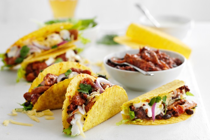A slate of tacos filled with pork, beans, red onion, soured cream and coriander