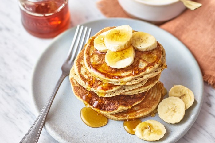 Protein pancakes A stack of protein pancakes topped with slices of banana and honey on a white plate