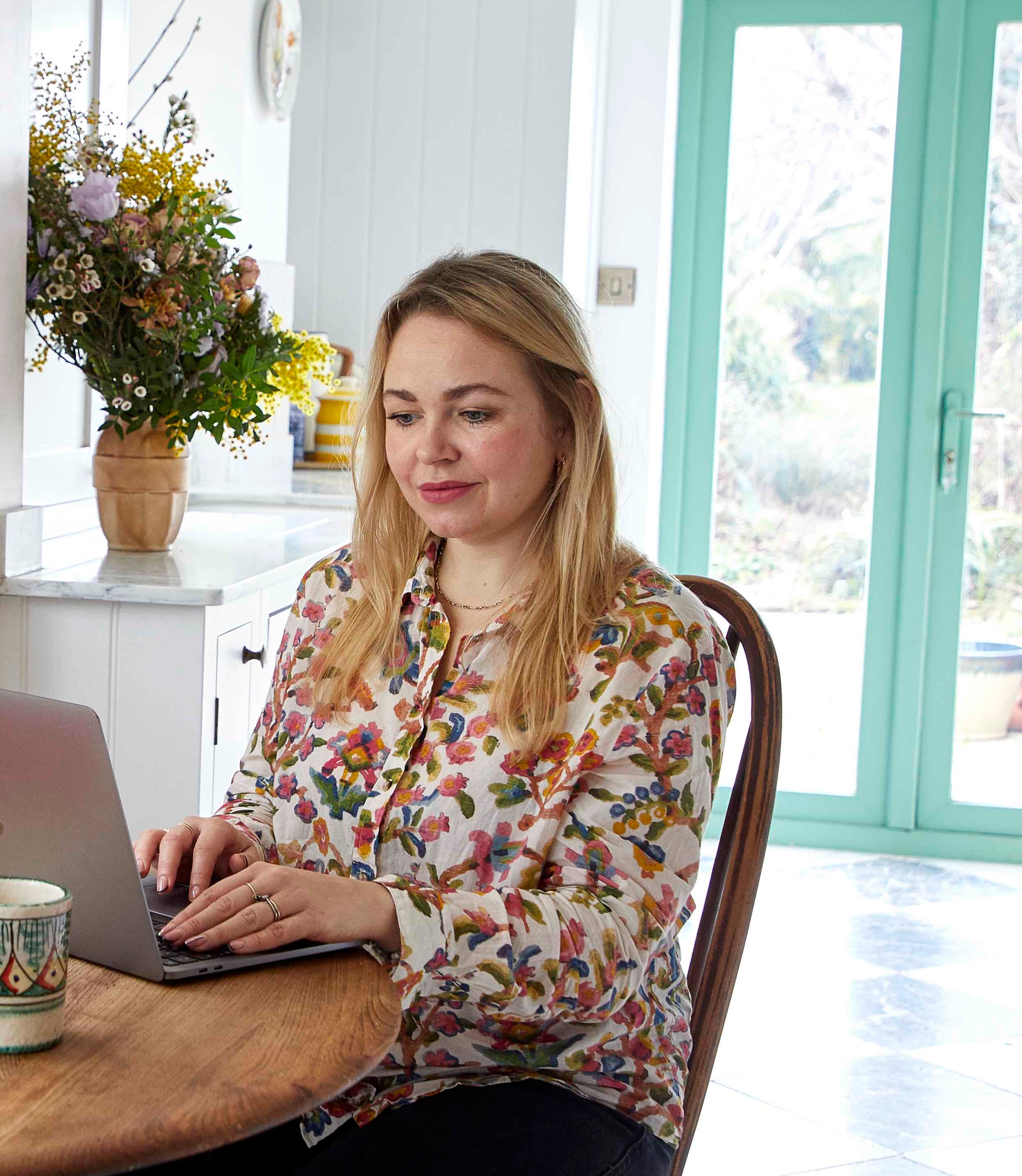Rosie Birkett Rosie Birkett in a floral shirt sat at her desk