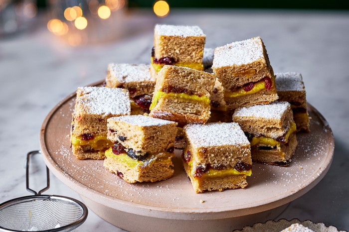 A batch of stollen bites presented on a cake stand alongside a sieve