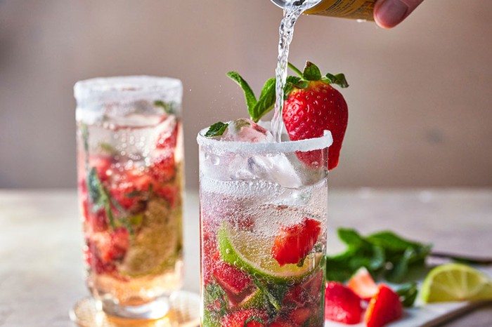 Strawberry mojito Two glasses of strawberry mojitos and fruit, hand pouring tonic water