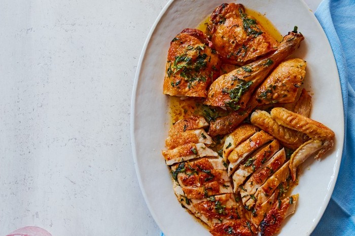 Tarragon chicken A white oval platter filled with sliced joints of chicken on a white and blue background