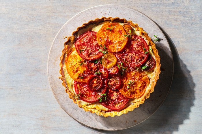 Tomato manchego tart A tomato tart on a round plate with a grey wood background