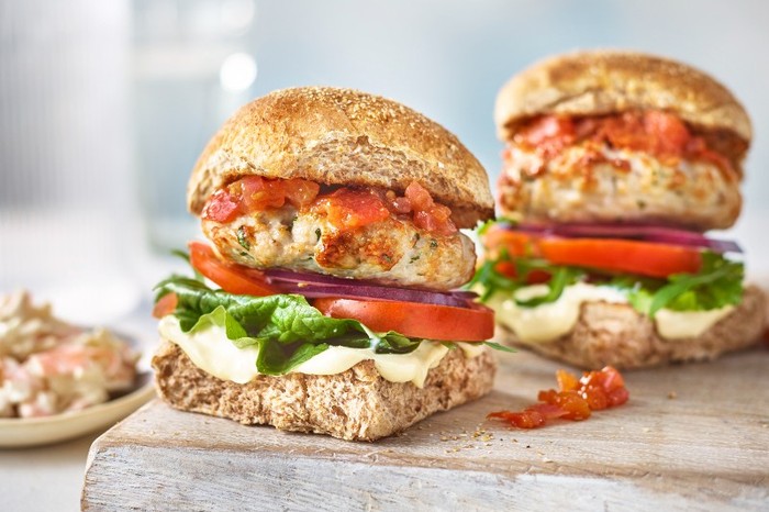 Healthy turkey burgers Two Turkey Burgers in Buns with Lettuce and Tomato on a Wooden Board