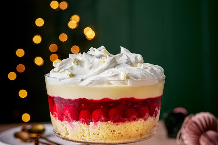 A layered raspberry and lemon trifle next to a few plates and cutlery