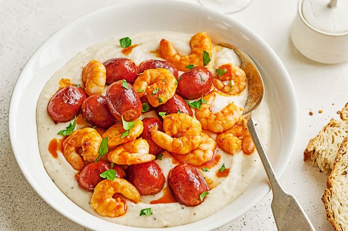 Warm white bean dip with chorizo and prawns Bowl of white bean dip topped with prawns and mini chorizo sausages