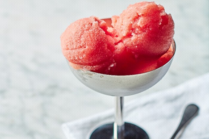 Watermelon sorbet A silver dessert cup filled with scoops of red sorbet on a white napkin