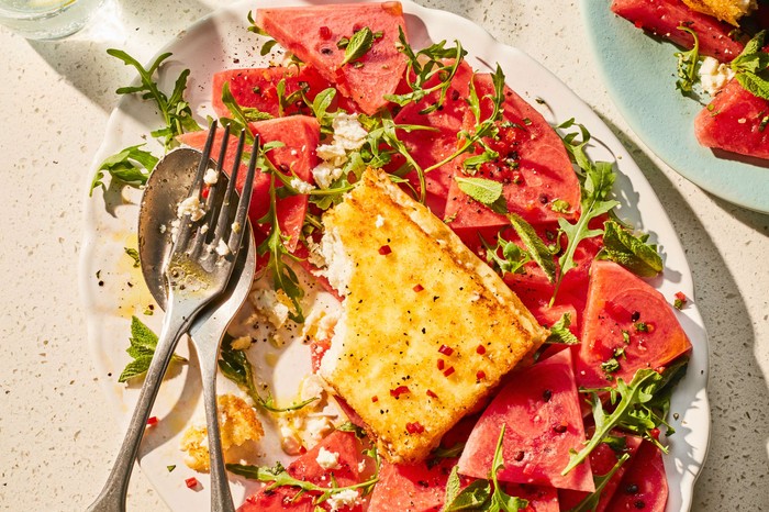 Crusted feta with rocket and watermelon salad Baked feta surrounded by watermelon slices on a large platter