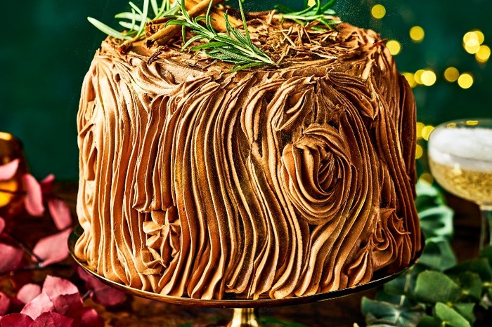 A woodland chocolate fudge cake on a gold cake stand with a green background