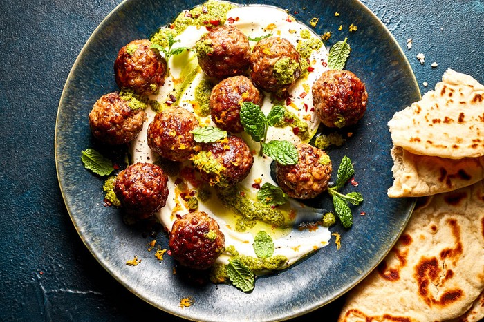 Zesty-lamb-meatballs-with-ricotta-and-mint-shatta Plate of meatballs in a sauce next to flatbreads